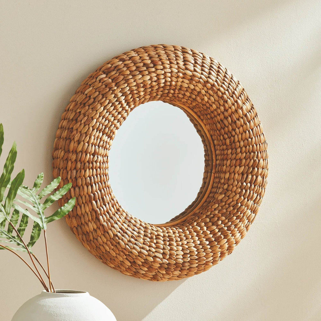 Wall-mounted round mirror shown with indoor plant and furniture to highlight scale and styling versatility.