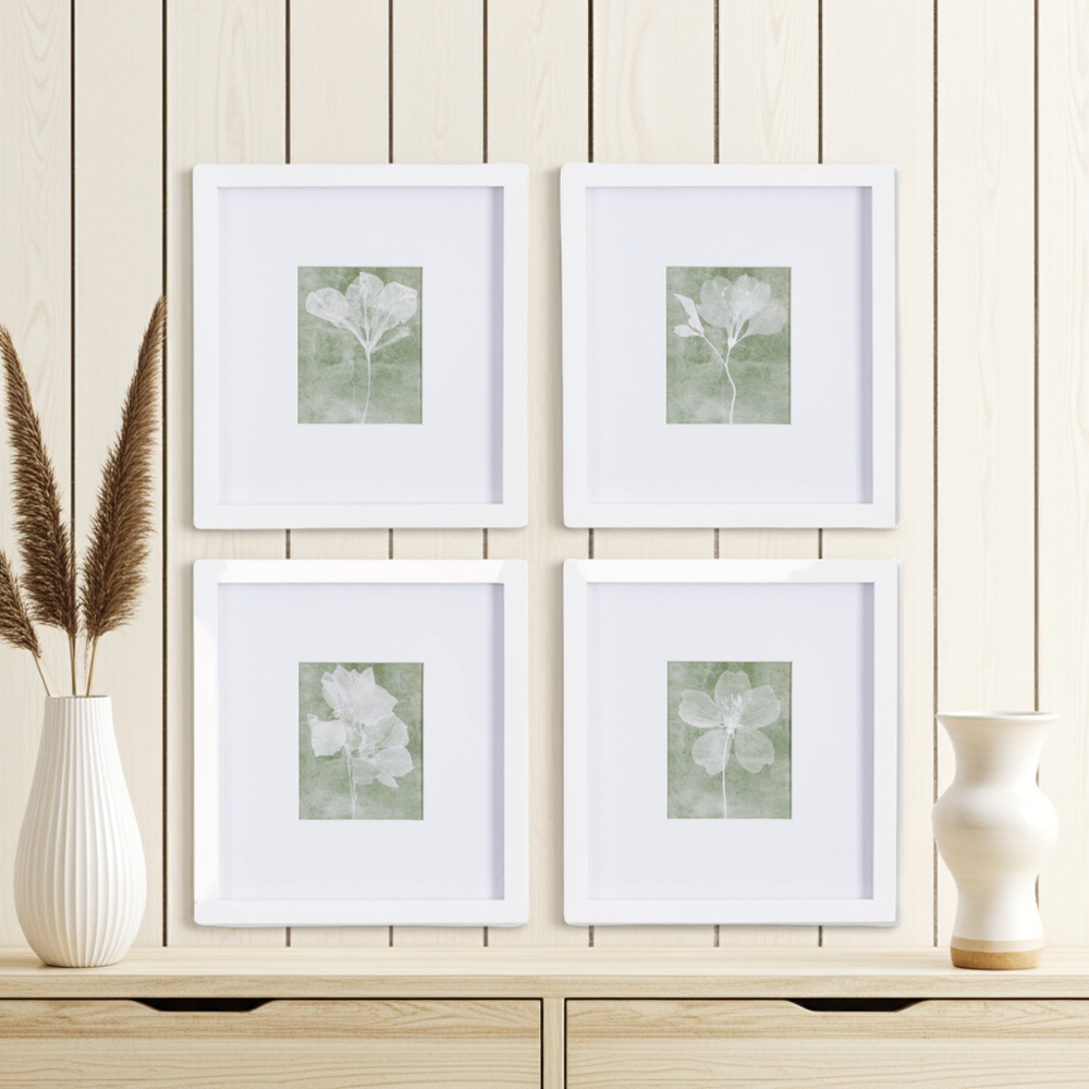 Close-up of framed green floral prints with white mats styled against neutral wood paneling
