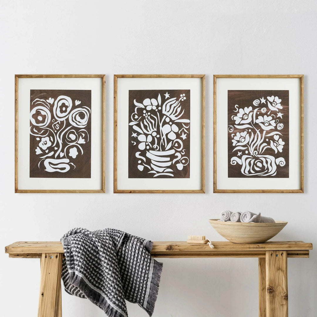 Set of vintage botanical wall art prints in bamboo-style frames displayed above a rustic bench with neutral spa decor

