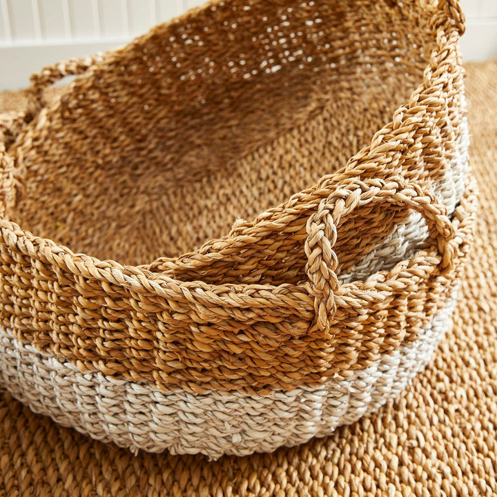 Close-up of stacked seagrass baskets showing braided handle construction and natural woven texture – Coastal Casual.

