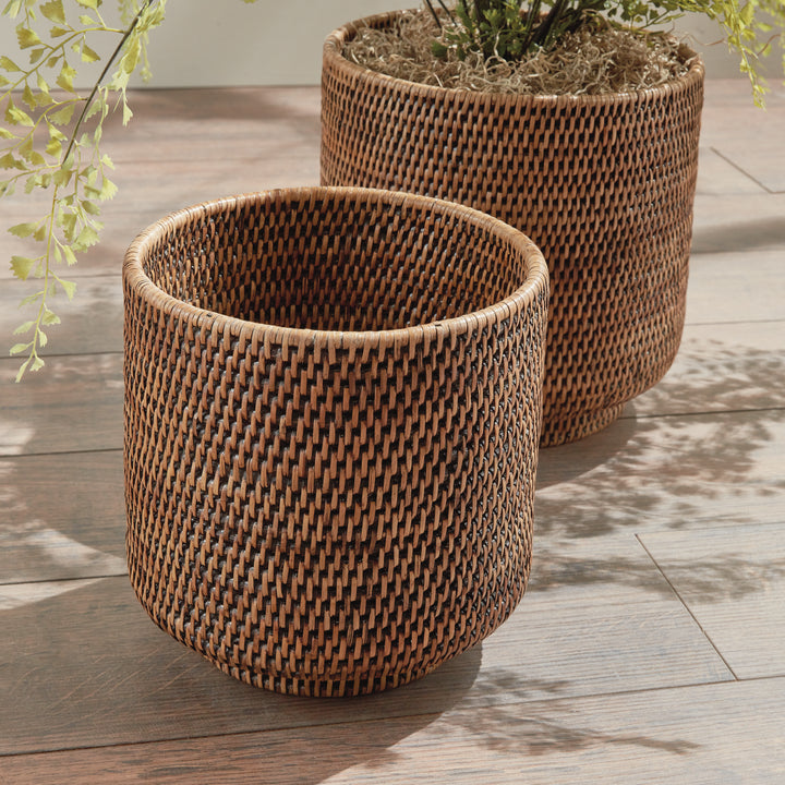 Brown rattan cachepots close-up on a wooden floor, showing woven sides and greenery in the larger pot - Coastal Transitional