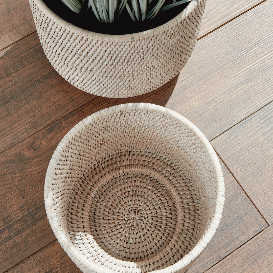 Whitewash rattan cachepots viewed from above on a wooden floor, showing woven interior beside foliage - Coastal Transitional