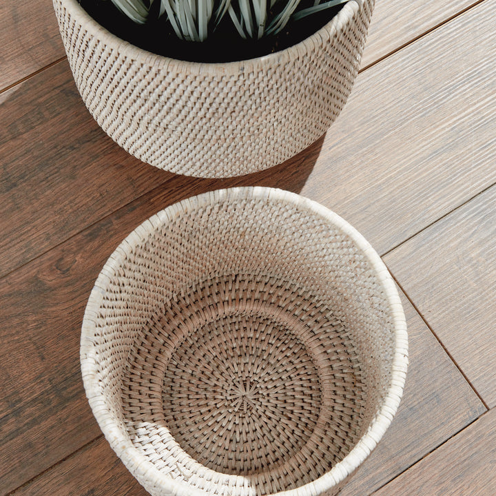 Whitewash rattan cachepots viewed from above on a wooden floor, showing woven interior beside foliage - Coastal Transitional
