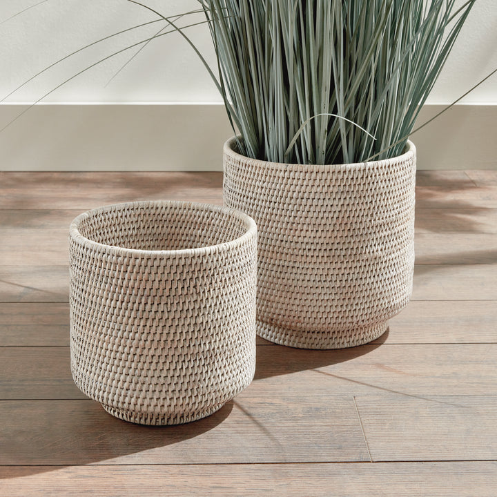 Whitewash rattan cachepot set styled on a wooden floor, with foliage rising from the larger woven pot - Coastal Transitional