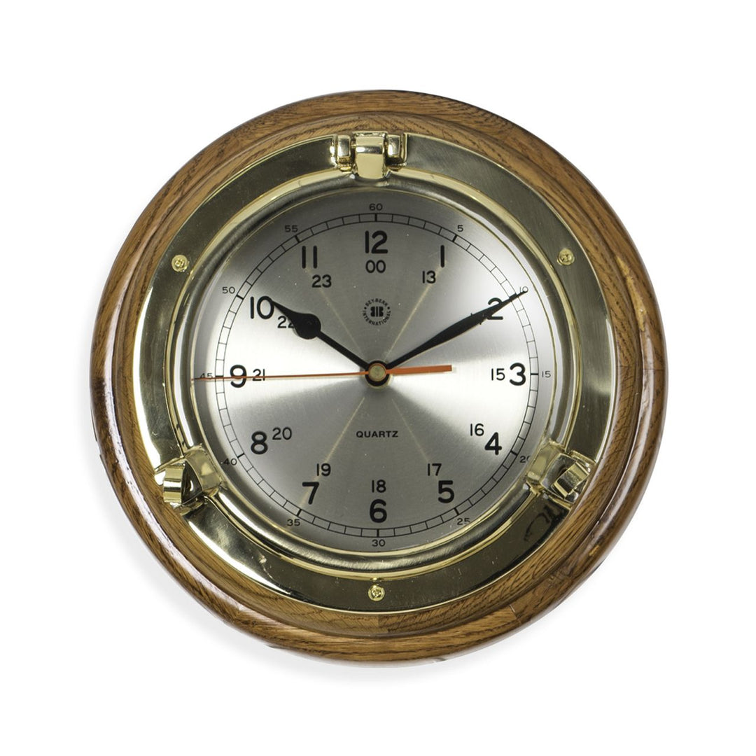 Solid brass porthole wall clock with brushed metal dial and oak wood surround shown close detail Nautical Classic style
