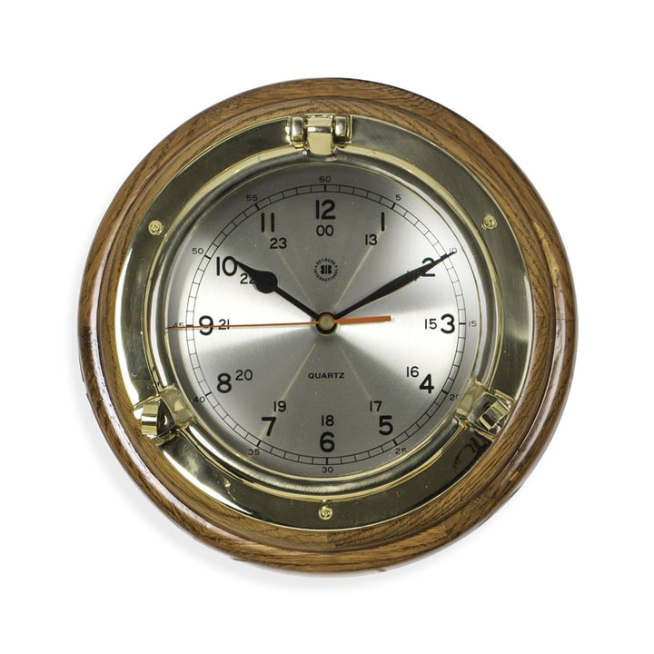 Solid brass porthole wall clock with brushed metal dial and oak wood surround shown close detail Nautical Classic style