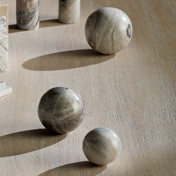 Brown and white marble orbs on a wood tabletop beside an arch sculpture, showing graduated sizes and veining. Modern Organic