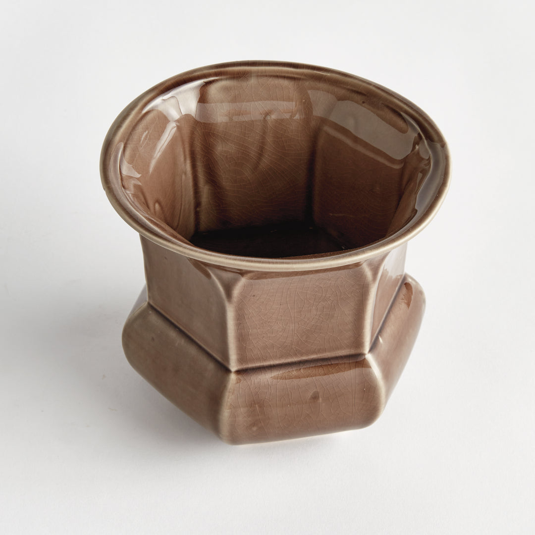 Angled view of a brown reactive glaze ceramic planter showing its flared rim and faceted sides against white, Traditional