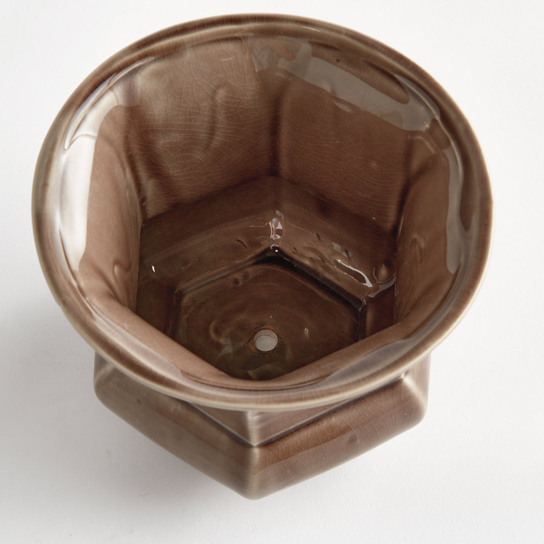 Overhead view into a brown glazed ceramic planter showing its faceted interior and drainage hole on plain white, Traditional