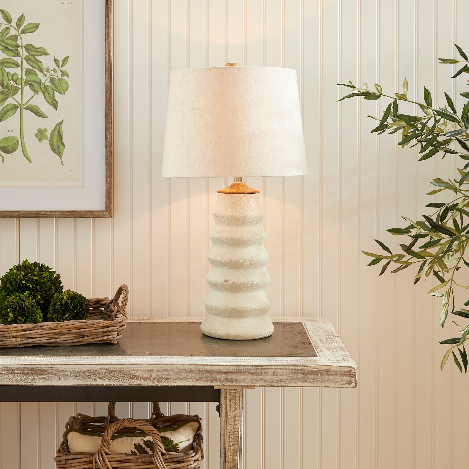 Enhance your living area with the Adria Table Lamp. This elegant table lamp features a natural cream eco-mix with a unique pitted texture, creating a lasting and warm white glow. The tapered shade adds a touch of sophistication to any living room.