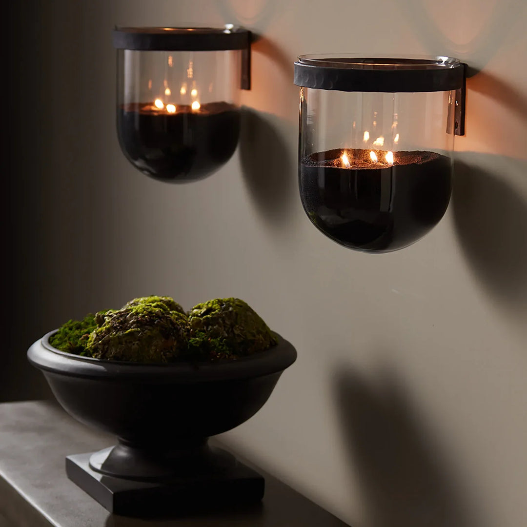 Black candle sand styled in glass wall sconces with multiple flames creating minimalist modern candlelight ambiance