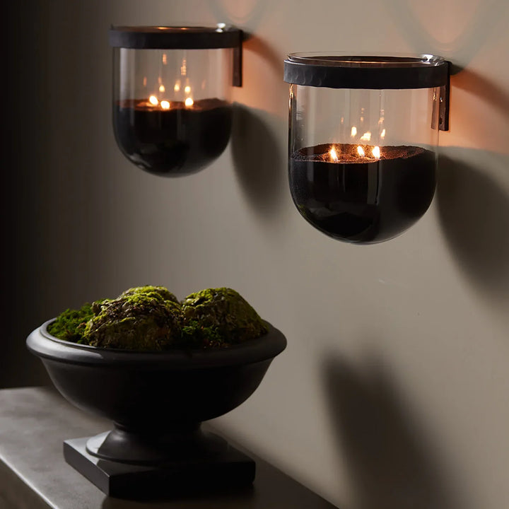 Black candle sand styled in glass wall sconces with multiple flames creating minimalist modern candlelight ambiance