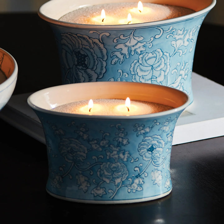 Close-up of candle sand in blue and white ceramic vessel showing multiple lit wicks and fine granulated wax texture