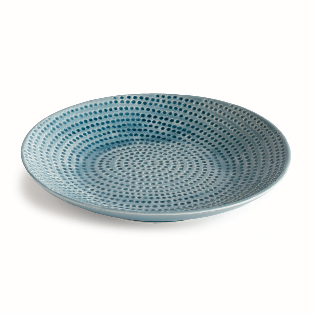 Carys round blue decorative plate with a gently curved rim and off-center dotted reactive glaze on a pale background. Coastal