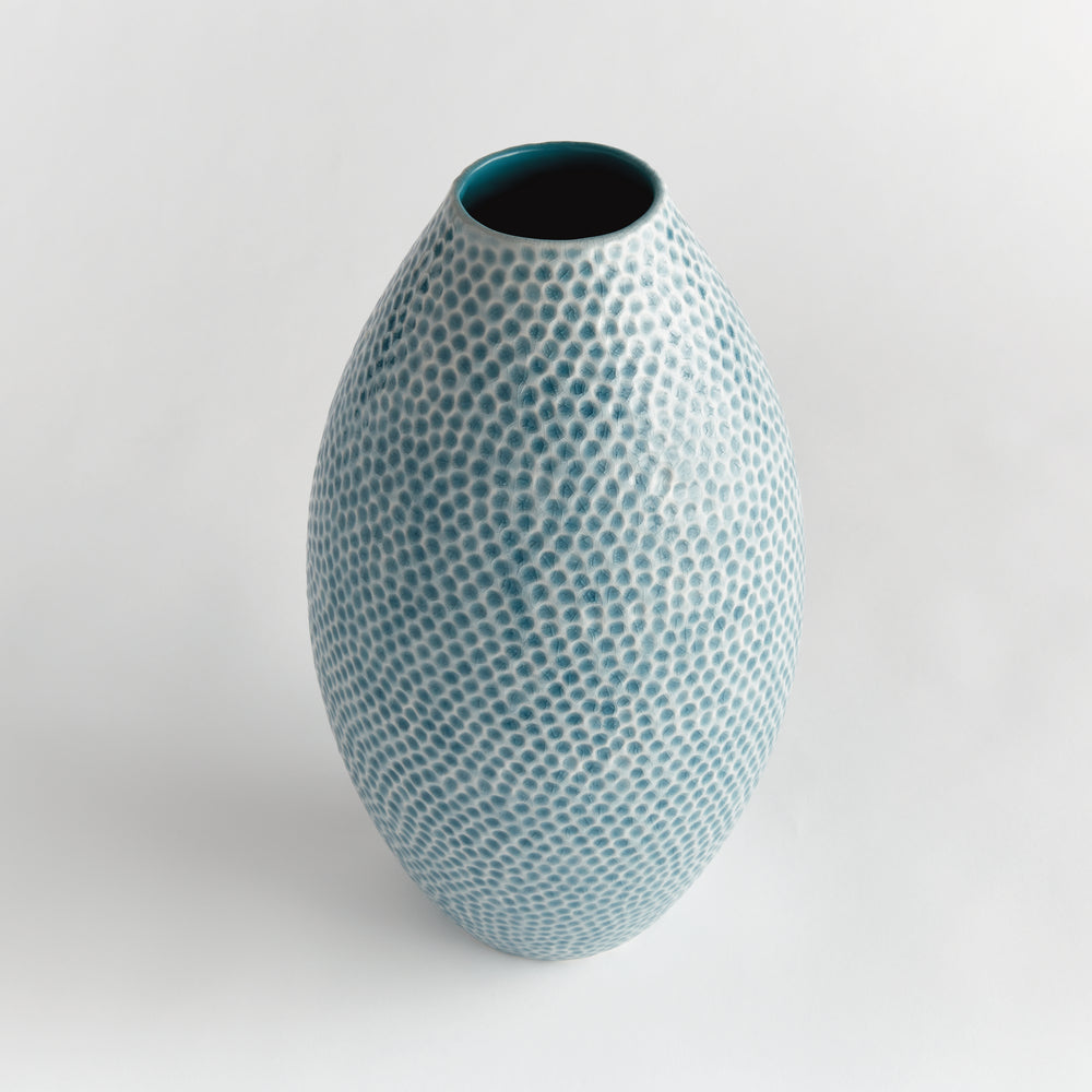Angled view of Carys tall blue ceramic vase showing the open neck and rounded dimpled body against a pale background. Coastal