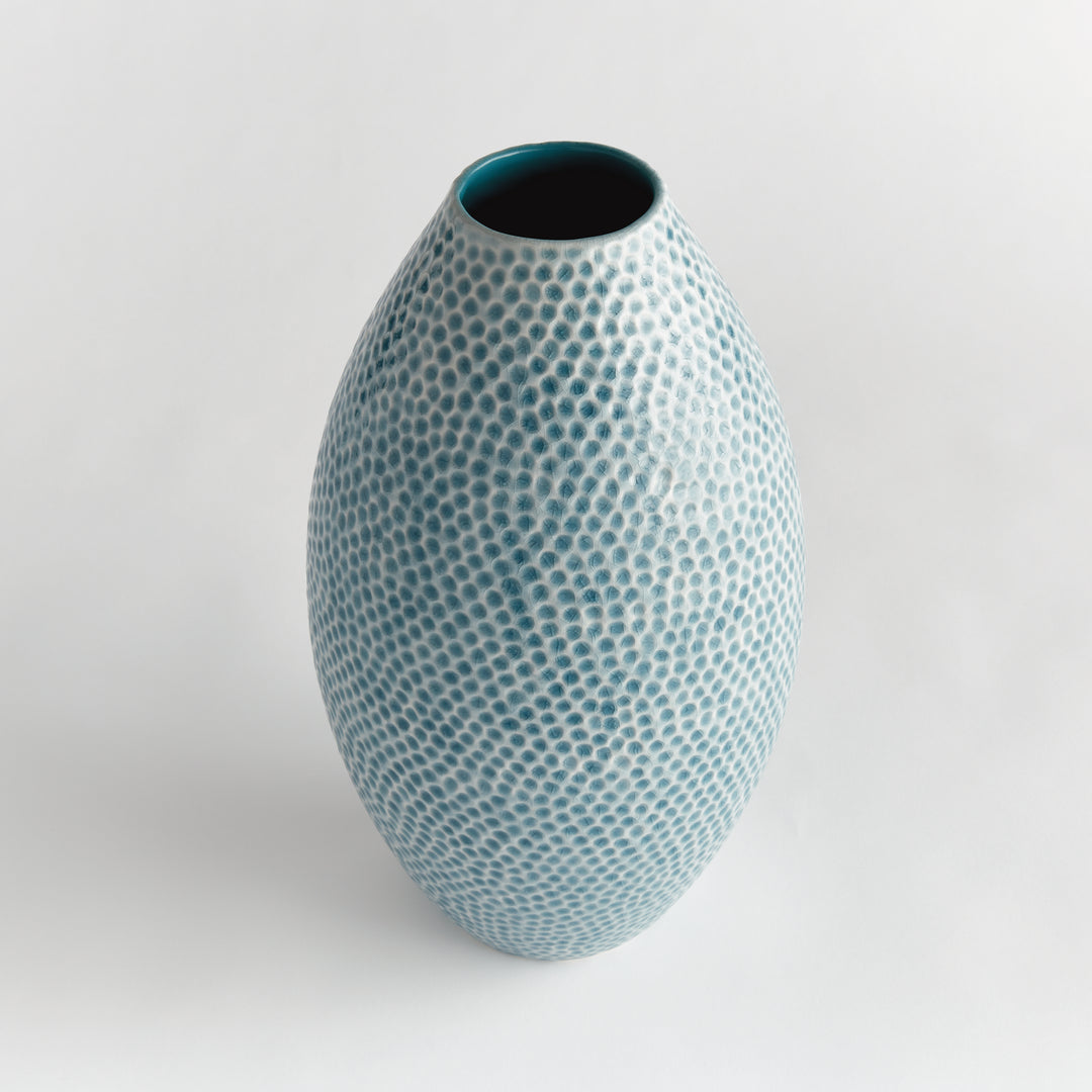Angled view of Carys tall blue ceramic vase showing the open neck and rounded dimpled body against a pale background. Coastal
