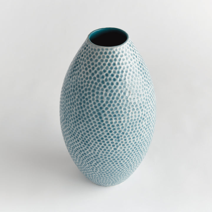 Angled view of Carys tall blue ceramic vase showing the open neck and rounded dimpled body against a pale background. Coastal