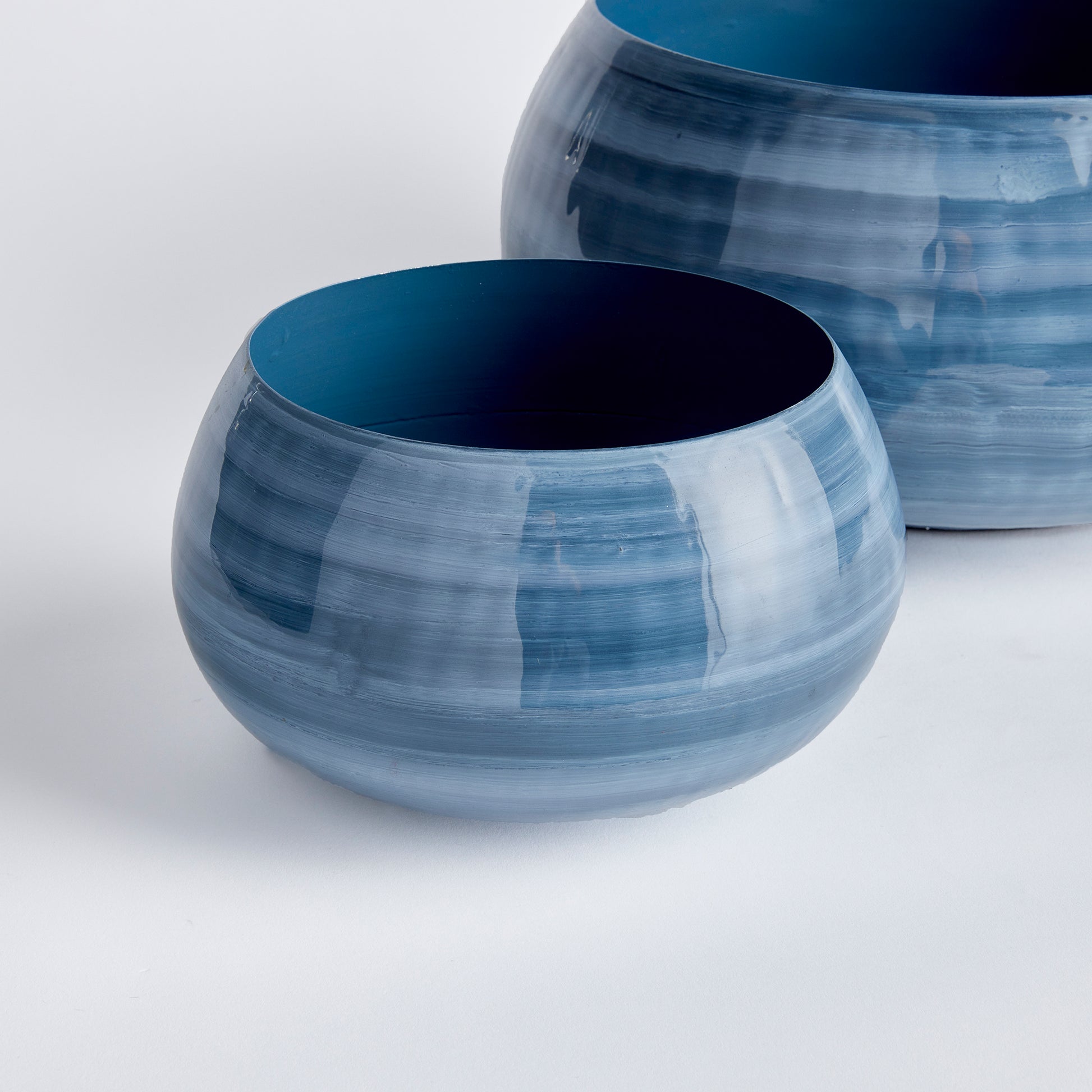 Featuring a delicate swirl pattern inspired by coastal hues of blue and gray, these Andrey Decorative Bowls are a stunning set of two crafted from enameled iron. Each bowl is hand-painted with precise, lightweight strokes, using a sophisticated horizontal design. The modern artistry and portable elegance make this set a unique addition to your tableware.