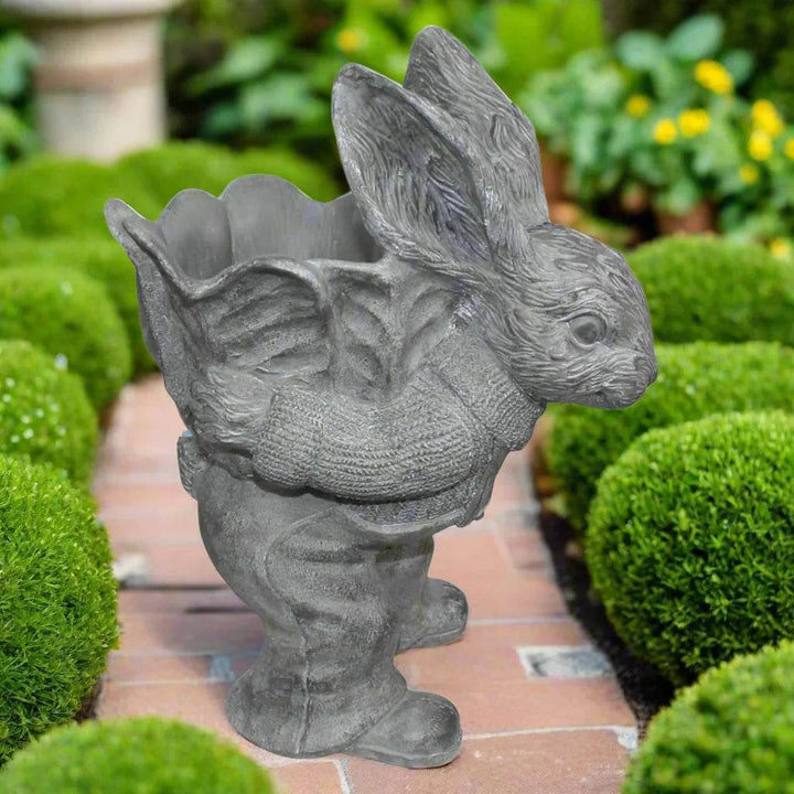 Cement bunny planter displayed in a garden setting on brick path, surrounded by trimmed hedges