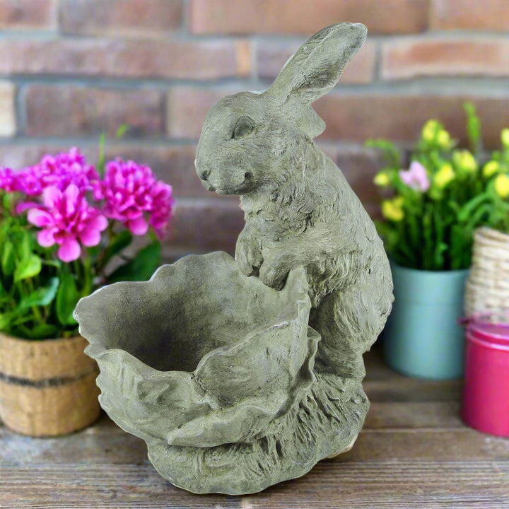 Cement bunny planter with textured detail displayed on rustic wood surface with pink and yellow spring flowers