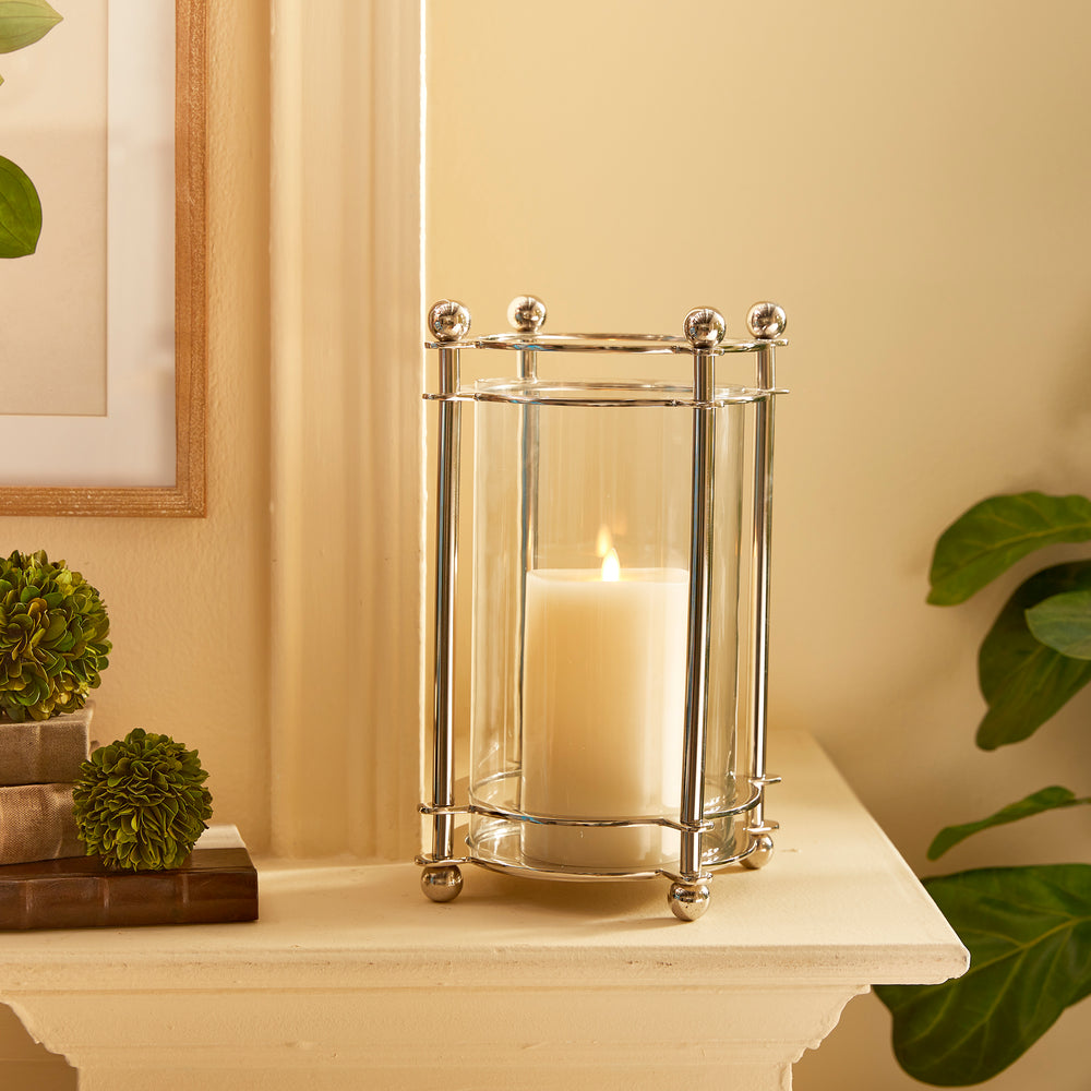 Chrome hurricane candle holder styled on mantel with greenery and candlelight
