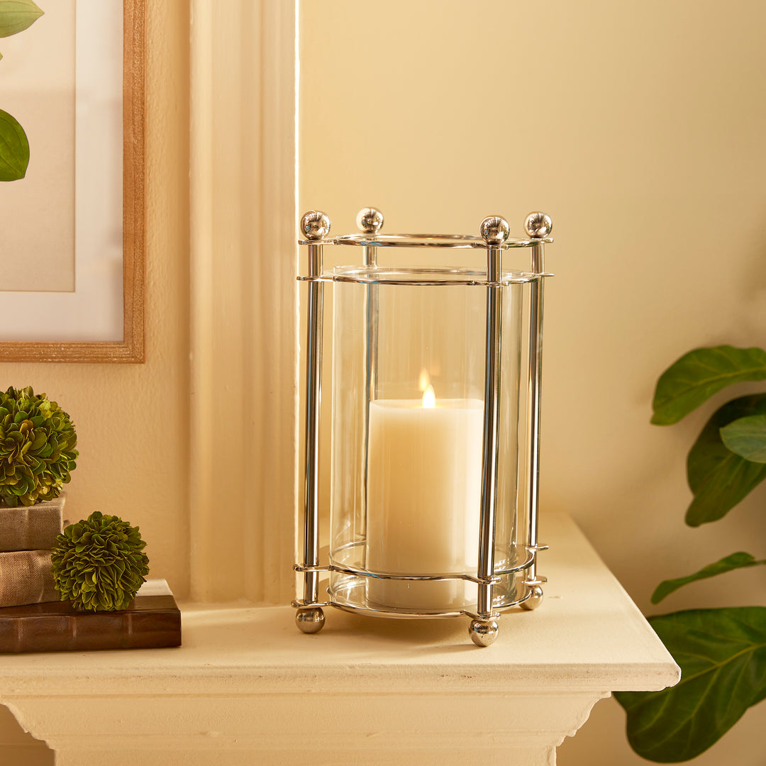 Chrome hurricane candle holder styled on mantel with greenery and candlelight
