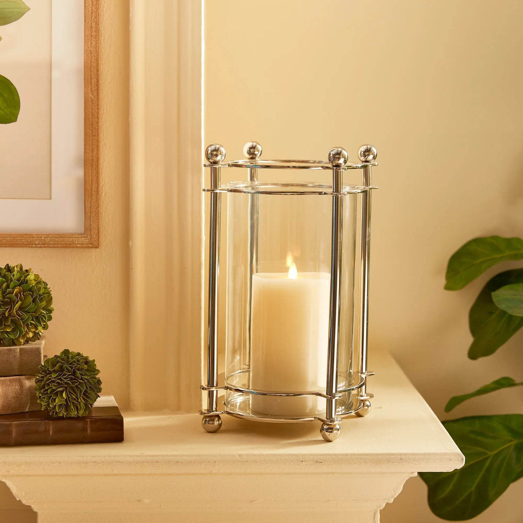 Chrome hurricane candle holder styled on mantel with greenery and candlelight
