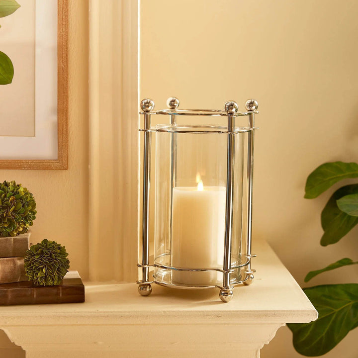 Chrome hurricane candle holder styled on mantel with greenery and candlelight
