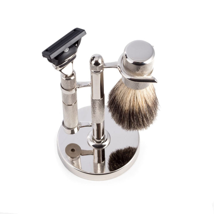 Top view of chrome razor and pure badger brush shaving set with diamond-cut handles on matching chrome stand, includes one blade installed.