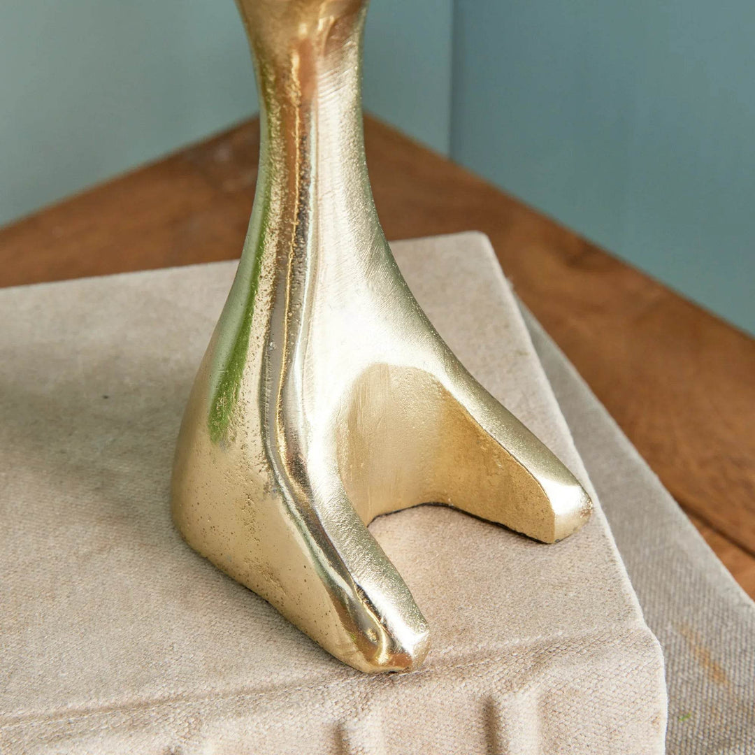 Close-up of gold aluminum jackrabbit foot resting on neutral fabric-covered book – Modern Coastal.