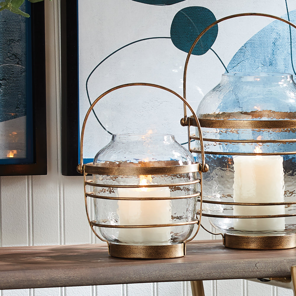 Pair of hammered glass hurricanes with antique gold iron detail, styled on console table with wall art – Coastal