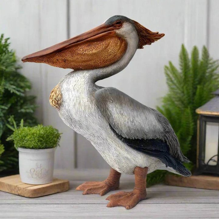 Coastal pelican statue displayed indoors with plants and lantern for beach-inspired decor