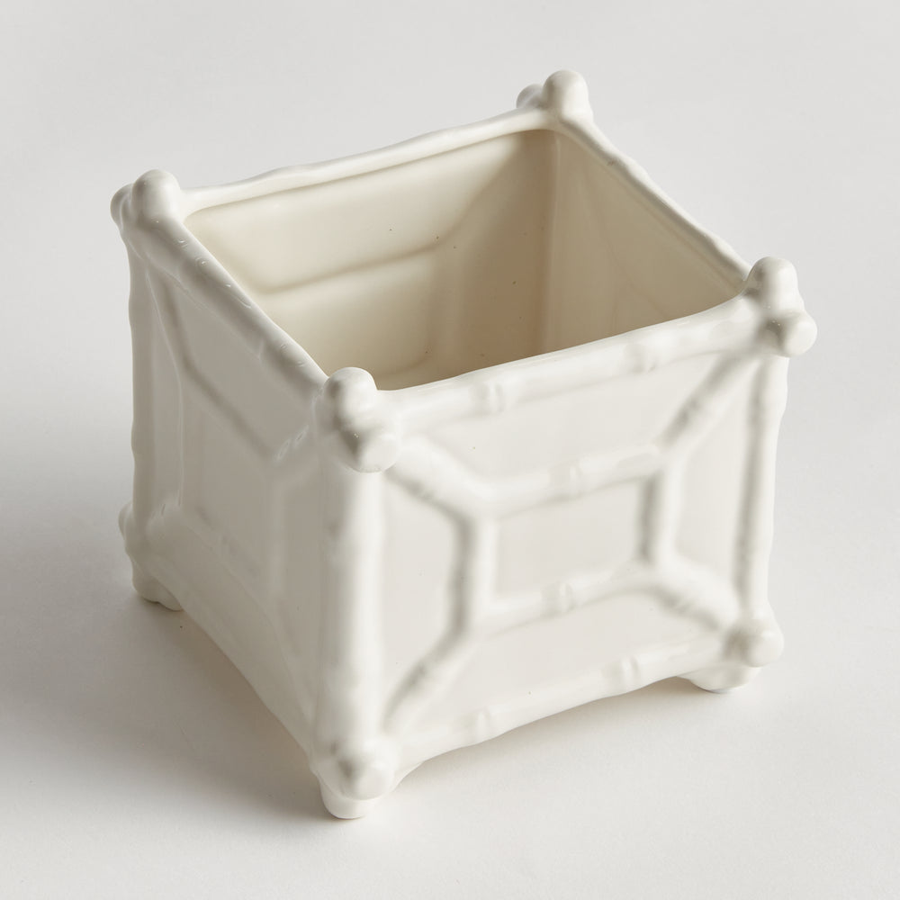Small white ceramic cachepot viewed at an angle, showing square-shaped sides and raised bamboo-inspired framing | Traditional