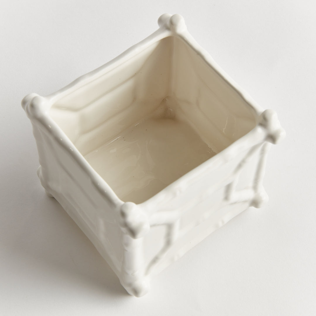Top view into a small square white ceramic cachepot, showing its pale interior and raised corner decoration | Traditional