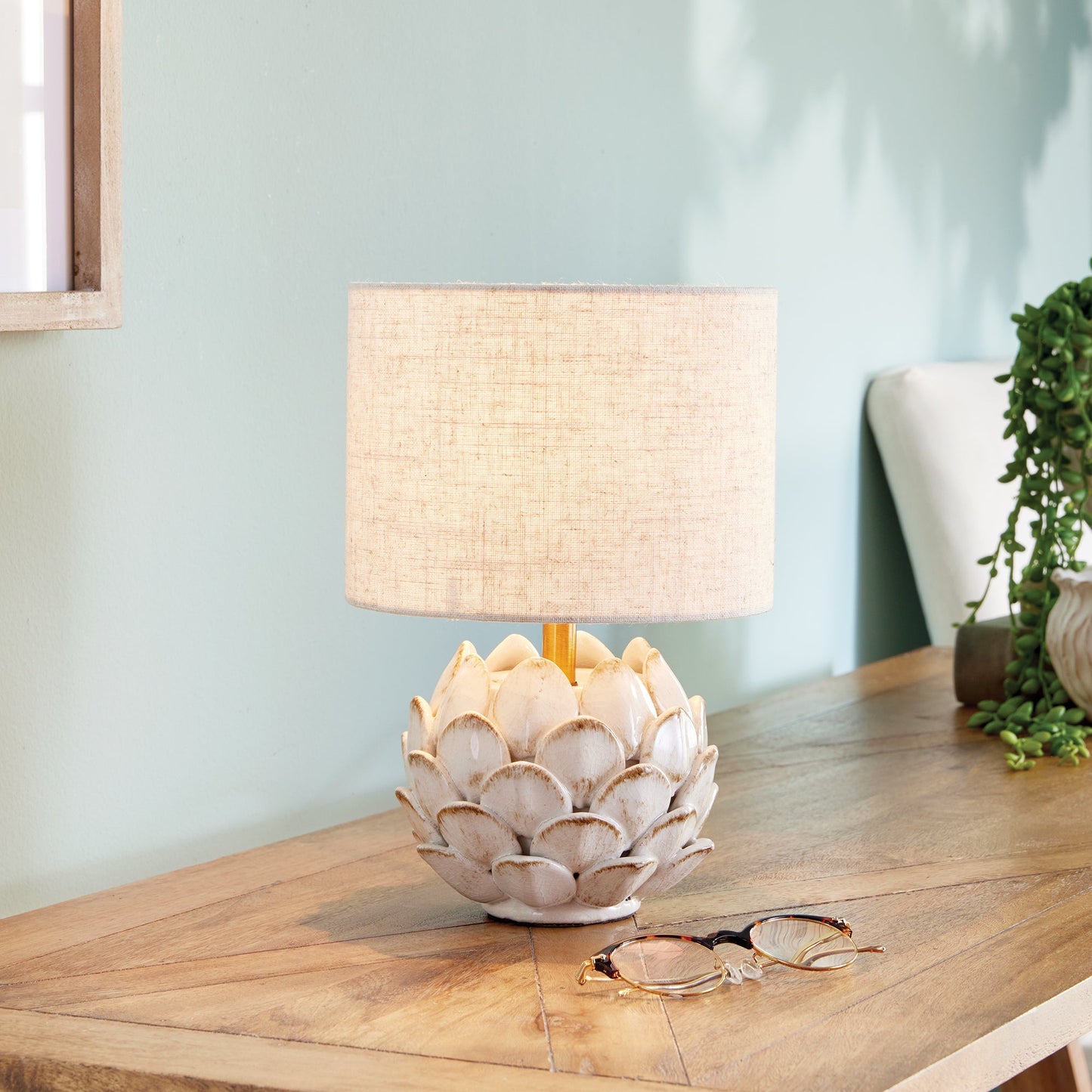 Transform your space with this exquisite ceramic table lamp, inspired by the intricate beauty of artichokes. Hand-finished with antique edges, it exudes a timeless elegance. Complete with a natural linen shade, this lamp is the perfect addition to any sophisticated and exclusive setting.