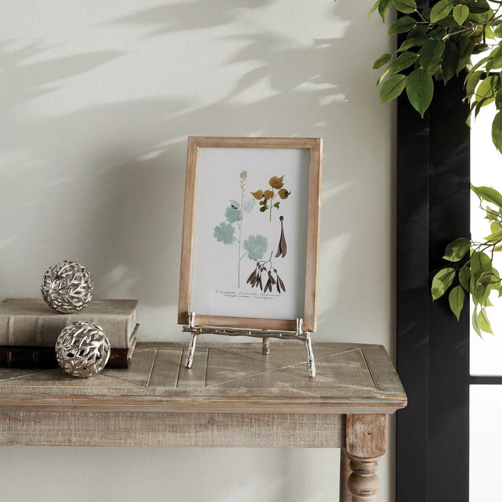 Elevate your decor with this sturdy and resilient silver easel, expertly crafted to exhibit platters, cookbooks, or small art pieces. The traditional aesthetic of bamboo-like silver details adds a timeless charm, while the versatile design allows for effortless display of various items.
