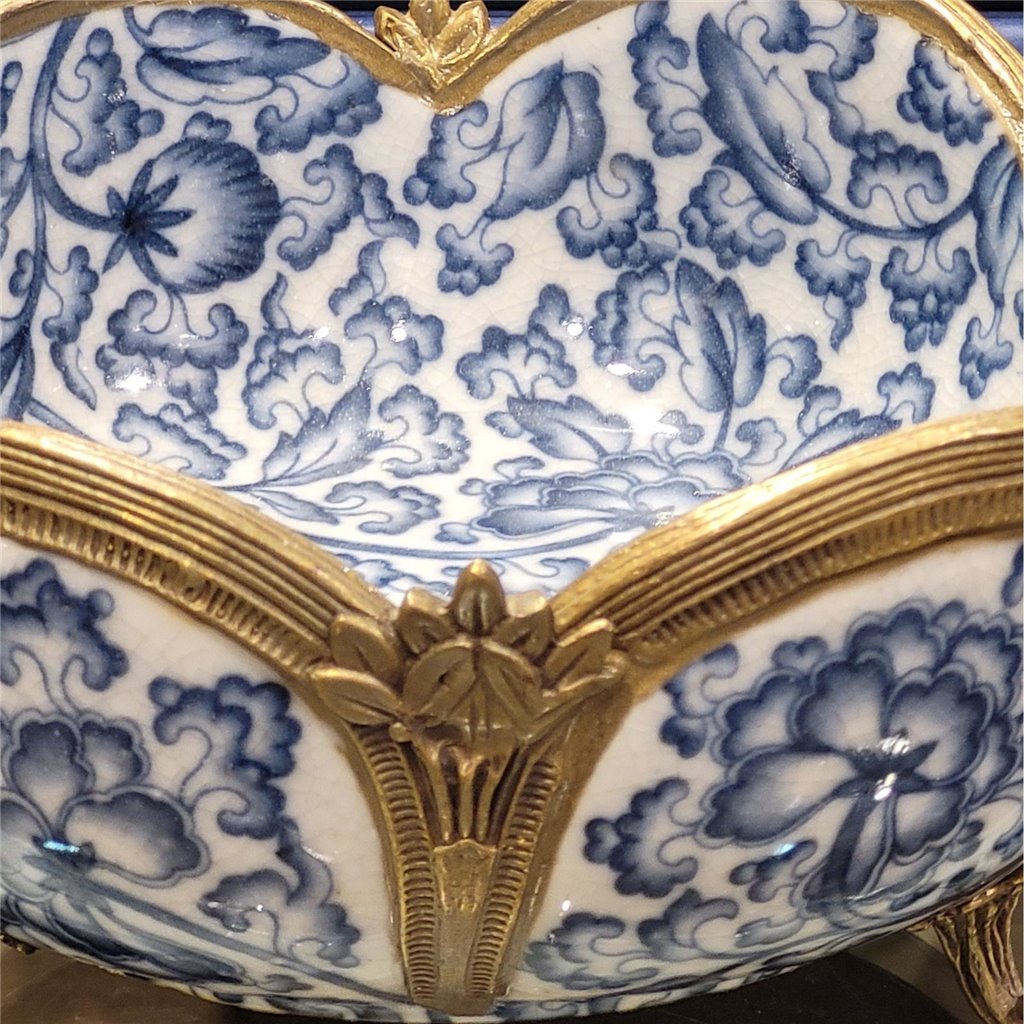 Blue and white porcelain bowl with bronze accents displayed on console setting – Transitional