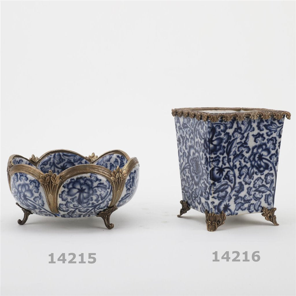 Blue and white porcelain decorative bowl shown next to matching square vessel with bronze accents – Transitional