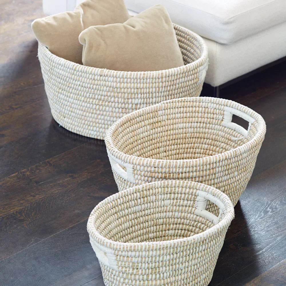 Decorative white rivergrass baskets placed beside sofa with throw pillows, styled in a modern organic room.