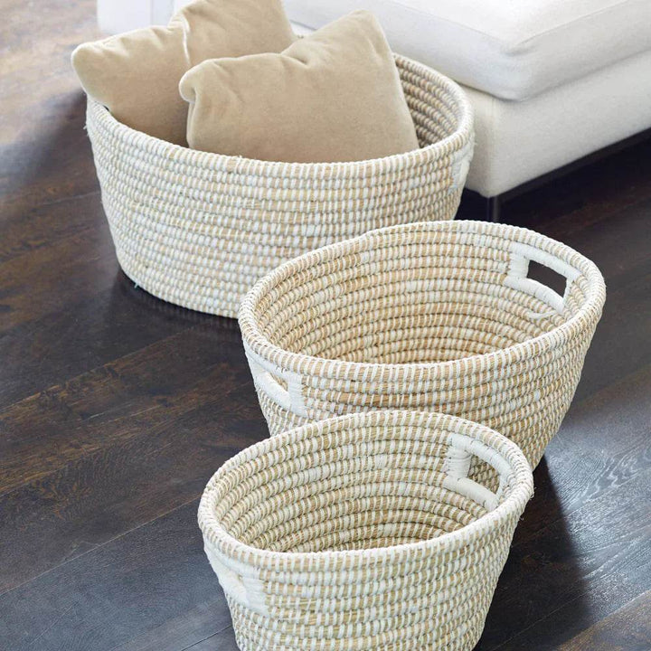 Decorative white rivergrass baskets placed beside sofa with throw pillows, styled in a modern organic room.