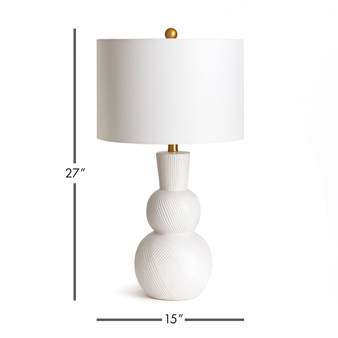 This traditional table lamp is crafted from clean white ceramic and features hand carved markings on the body, making it a perfect addition to any traditional setting. It is complemented by a white linen shade and a simple brass finial. Ideal for enhancing the ambiance of any living room or home decor.