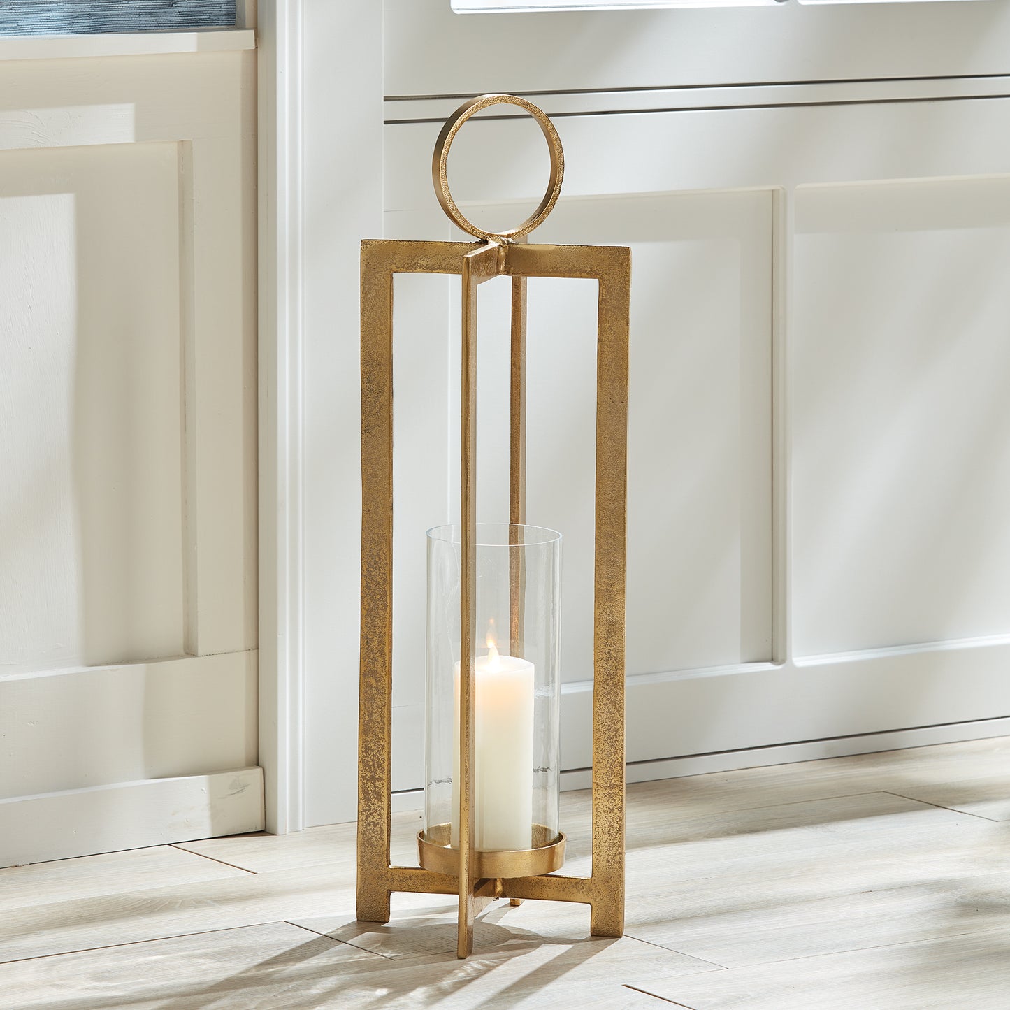 This lantern boasts a contemporary design and impressive size, commanding attention. The detailed footing raises the candle, while the spacious round handle adds an element of refinement. It would make a chic addition to a mantle, front entry, or any space. Its sleek and modern design complements any setting. The intricate footing lends an air of elegance, and the sizable round handle offers effortless portability. An ideal choice for showcasing on a mantle or in a front entryway.