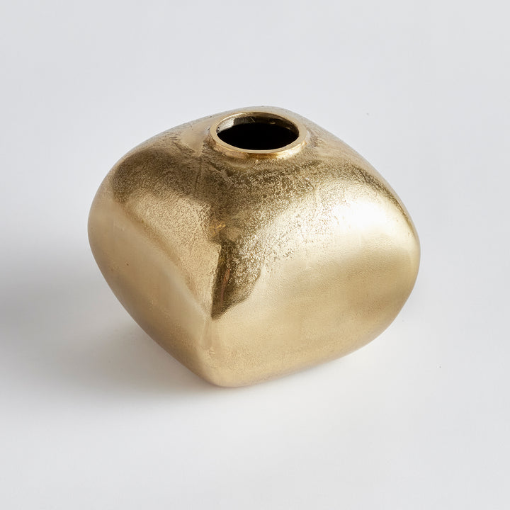 Crafted with precision from cast aluminum, the Asha Golden Vase boasts a unique shape, combining rounded curves with defined edges. Display faux stems or use it as a standalone accent piece on your ottoman, bookshelf, or home office desk. A versatile addition to any room, this vase exudes elegance and charm. Perfect for both decorative and functional purposes, it is a must-have for any decor enthusiast.