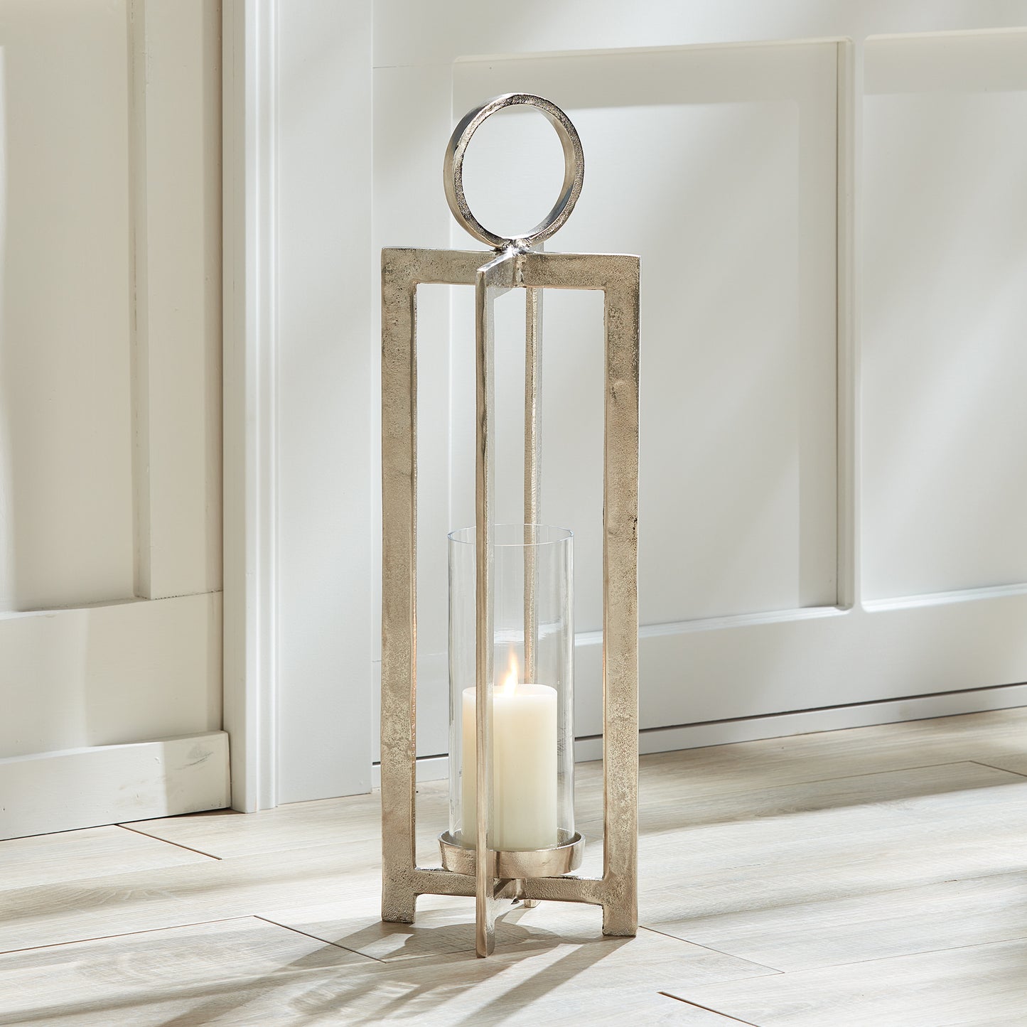 Featuring an impressive scale and sleek modern design, this lantern is guaranteed to make a statement. Its footed detail elevates the candle, while the large round handle adds a touch of sophistication. Perfect for any space, from a mantle to a front entry and beyond, this lantern is sure to impress.