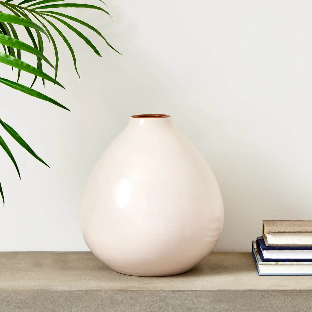 Wide ecru ceramic vase with rounded silhouette on stone console, styled with stacked books and plant – Modern Organic