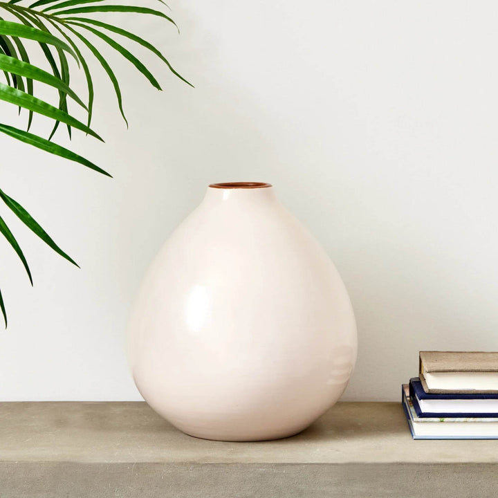 Wide ecru ceramic vase with rounded silhouette on stone console, styled with stacked books and plant – Modern Organic