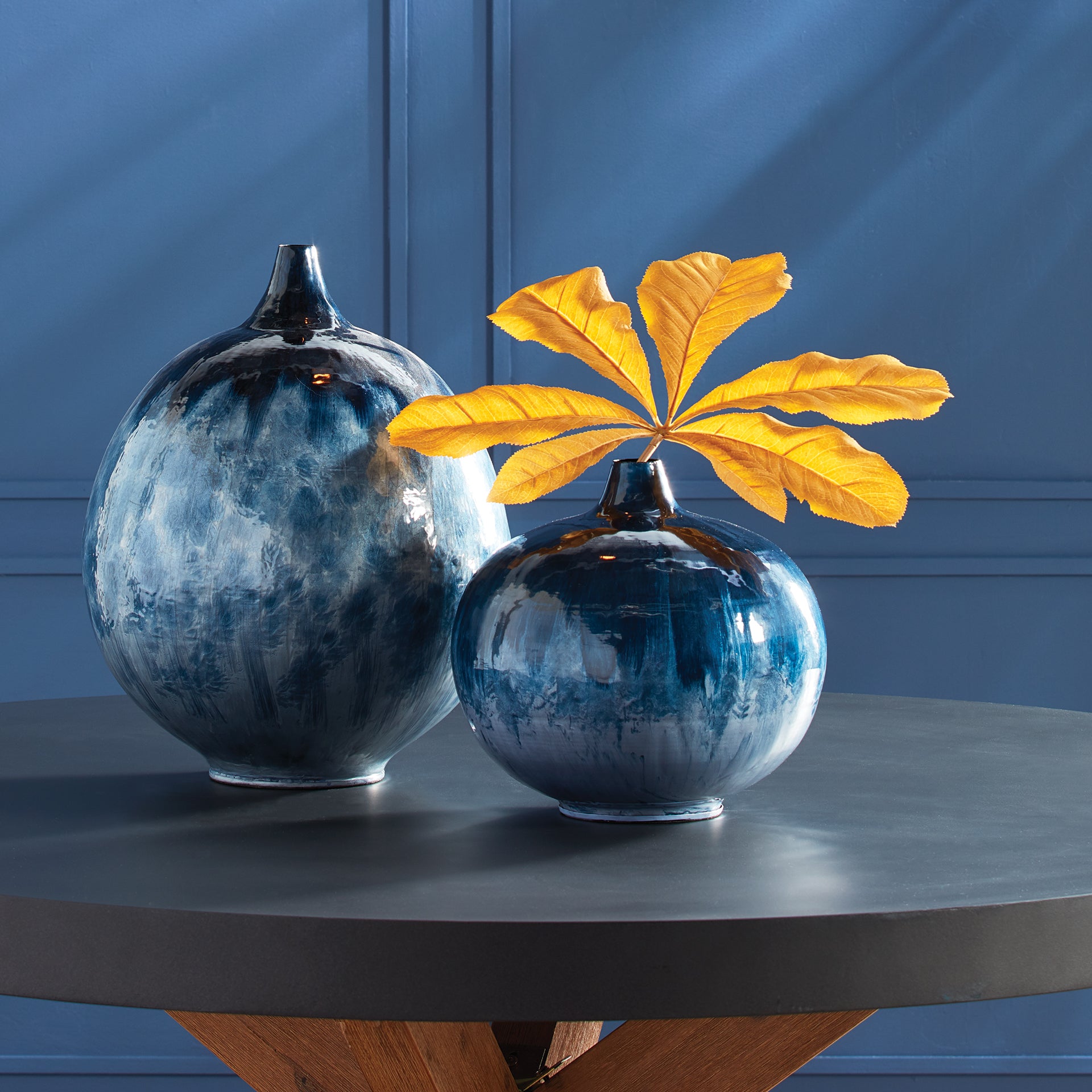 Crafted from lightweight enameled iron and hand-painted in a stunning ombre design inspired by nature, this Blue Round Vase Petite is the epitome of effortless elegance. The durable iron material gives it both strength and lightweight properties, while the organic blue tones add a touch of natural beauty. A perfect representation of understated sophistication.