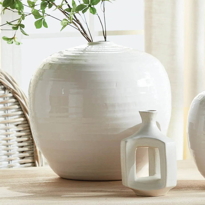 Large oatmeal stoneware vase holding leafy branches on a wood surface beside small pale ceramic accents | Modern Organic