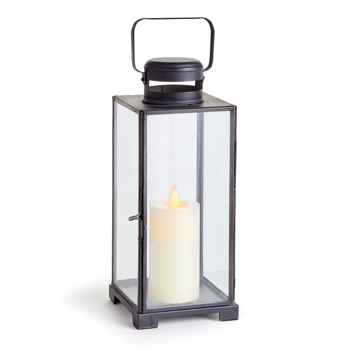 Emmett antique black iron lantern with clear glass panes, a top handle and a candle against a pale background. Transitional