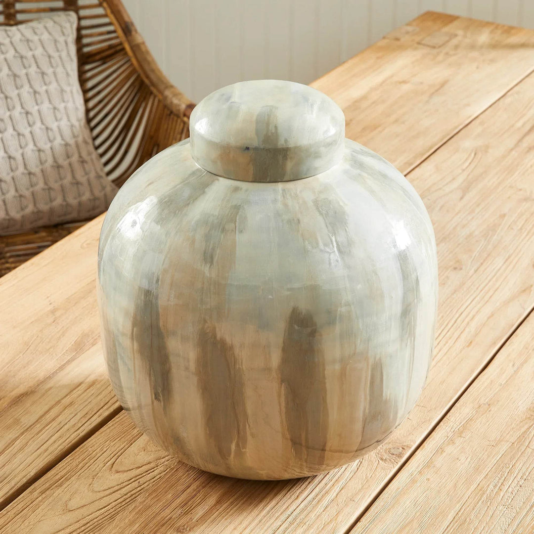 Neutral cream and taupe enameled iron lidded urn, rounded ginger-jar shape and dome lid, shown at an angle on tabletop vignette – Transitional
